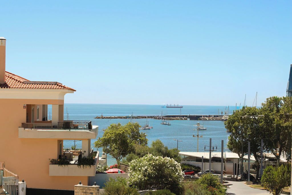Un edificio frente al mar con balcones que dan a un puerto deportivo con barcos y un barco a lo lejos.
