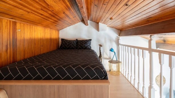 A bedroom with a wooden ceiling, a bed with a black and white patterned bedspread, a giraffe decoration, and a white railing. - House in Marseille-Estaque, Sleeps 6, Large Terrace (Marseille)