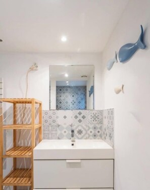 A bathroom with a white sink, a mirror, a wooden shelf, and a wall with a blue whale decoration. - House in Marseille-Estaque, Sleeps 6, Large Terrace (Marseille)