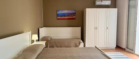 A bedroom with a bed, a wardrobe, a painting on the wall, and a ceiling light fixture.