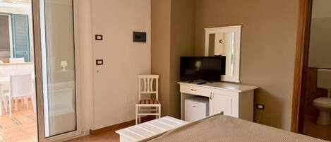 A bedroom with a bed, a television, a desk, and a chair.