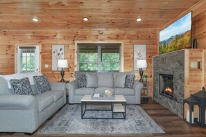 Un salon chaleureux avec une cheminée, des murs en bois et une grande fenêtre.