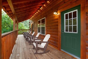 Eine Veranda aus Holz mit Schaukelstühlen und einer grünen Tür.