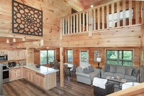 Eine Hütte mit Küche, Essbereich und Wohnzimmer, inklusive Sofa und Couchtisch.