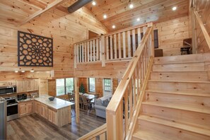 Ein Holzblockhaus-Interieur mit Küche, Essbereich und einer Treppe.