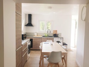 A modern kitchen with a built-in washing machine, a dining area with a table and chairs, and a window providing natural light.