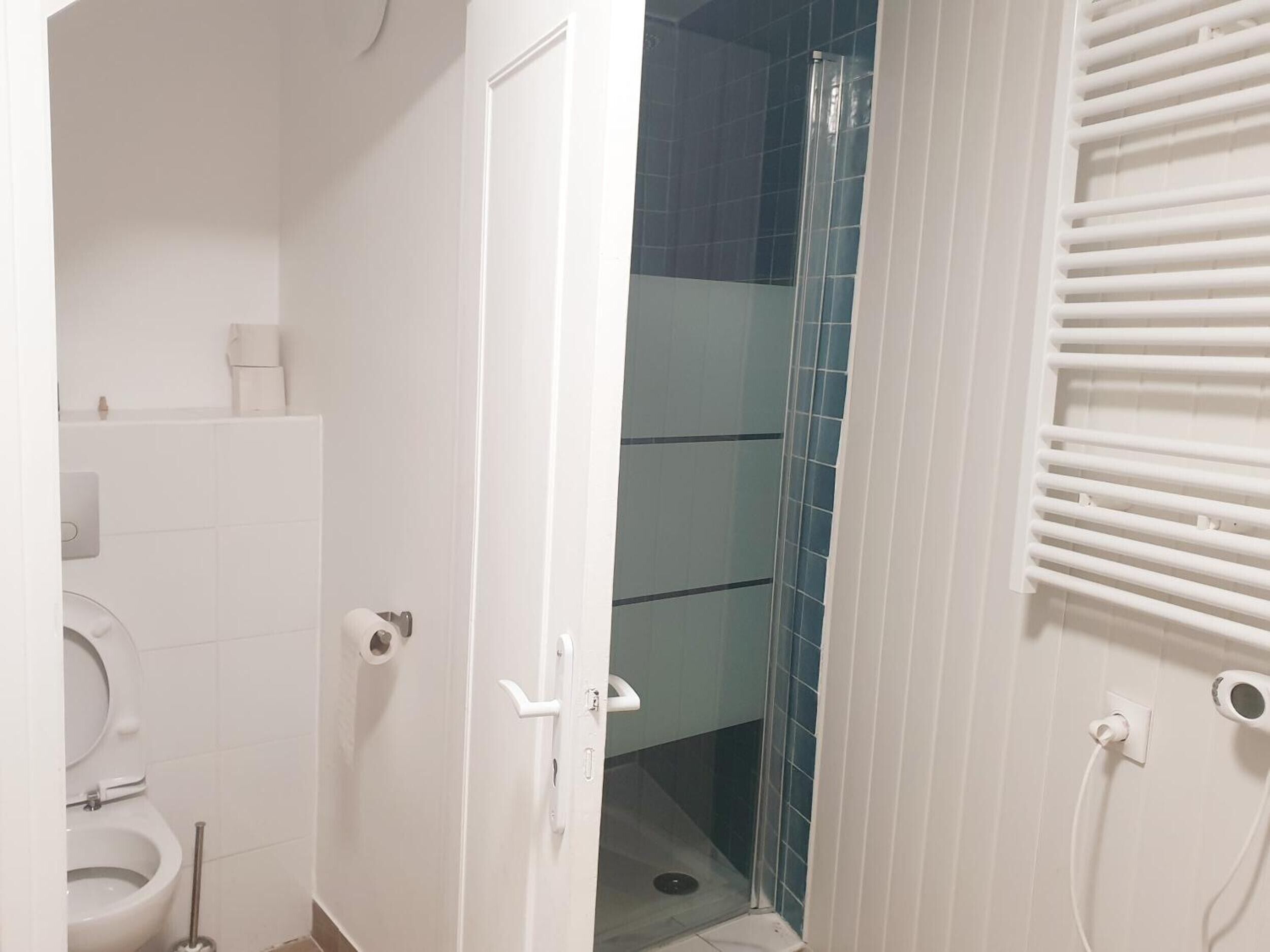 A bathroom with a toilet, a shower, and a towel rack.