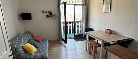 Un espacio habitable compacto con sofá, una mesa de comedor y una pequeña cocina.