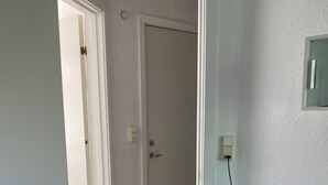 Ein Zimmer mit Fernseher auf einem Schrank, einer Tür zu einem anderen Raum und einem Teppichboden.