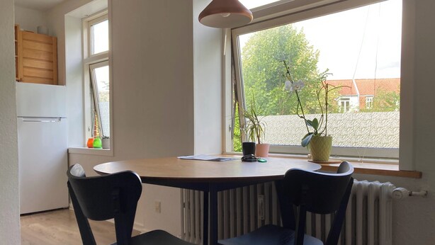 Eine Küche mit Fenster, einem Tisch mit Stühlen und einer Heizung.