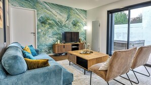 A modern living room with a large TV, a wooden coffee table, a sofa, and a chair. - Boreal - Maison Saint Gilles Croix de Vie (Saint-Gilles-Croix-de-Vie)