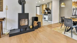 A modern living room with a fireplace, dining area, and kitchen in the background. - Boreal - Maison Saint Gilles Croix de Vie (Saint-Gilles-Croix-de-Vie)