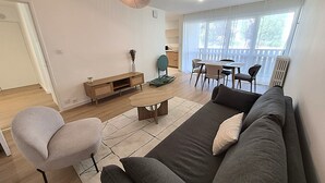A modern living room with a sofa, chairs, a coffee table, and a dining area with a table and chairs. - 2-bedroom apartment with balcony in Annecy (Annecy)