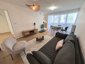 A modern living room with a sofa, chairs, a coffee table, and a dining area with a table and chairs. - 2-bedroom apartment with balcony in Annecy (Annecy)