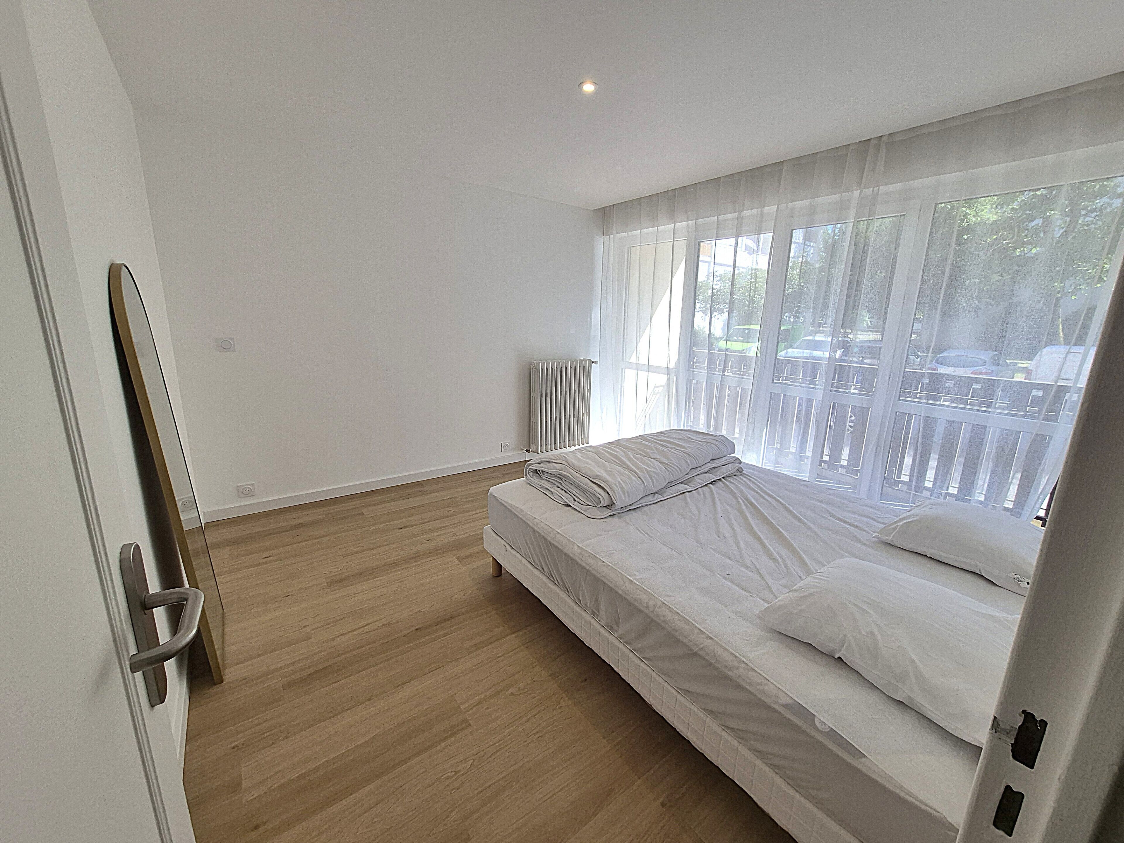 A bedroom with a bed, a radiator, and a view of the outside.