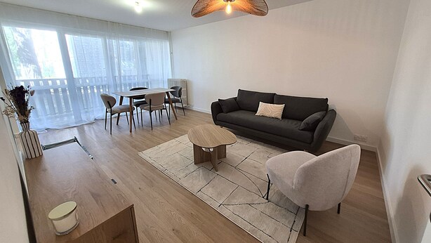 A modern living room with a sofa, coffee table, and dining area. - 2-bedroom apartment with balcony in Annecy (Annecy)