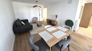 A modern living room with a sofa, chairs, a coffee table, and a dining table with placemats. - 2-bedroom apartment with balcony in Annecy (Annecy)