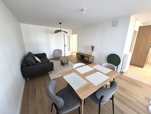 A modern living room with a sofa, chairs, a coffee table, and a dining table with placemats. - 2-bedroom apartment with balcony in Annecy (Annecy)