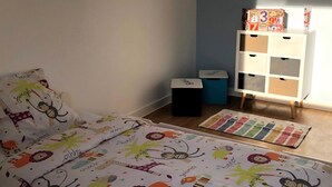 Una camera da letto per bambini con un letto, un mobile contenitore e un tavolino.