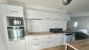 Una cucina moderna con mobili bianchi, un piano di lavoro in legno, un forno integrato e un lavello.