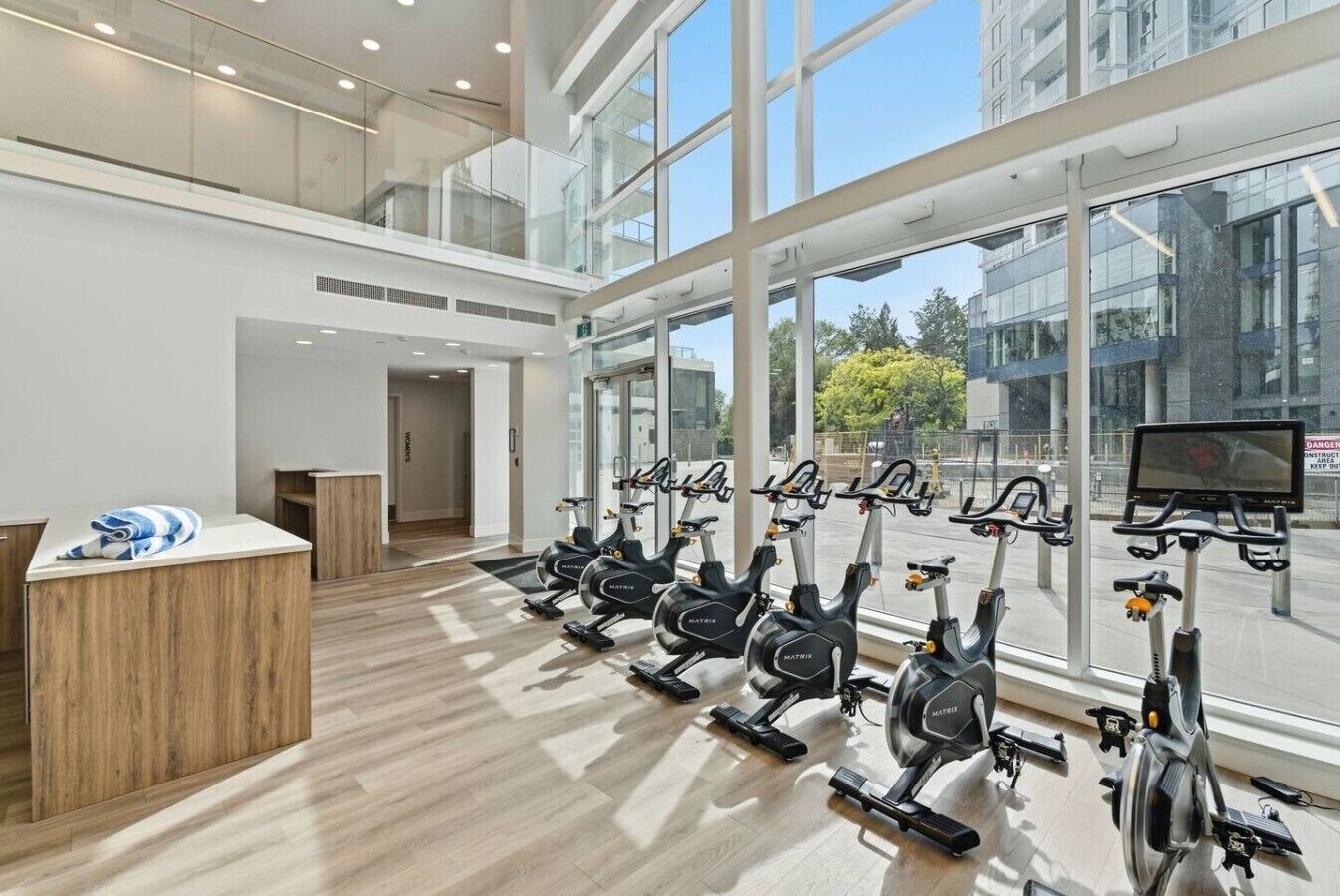 Ein Fitnessraum mit Ergometer, einer Rezeption und großen Fenstern.