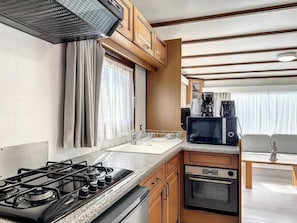 A compact kitchen with a gas stove, oven, microwave, and a small dining area with a table and chairs.
