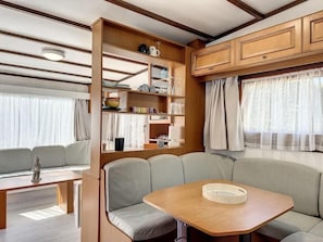 Interior compacto de una caravana, con comedor, asientos y armarios de almacenamiento.
