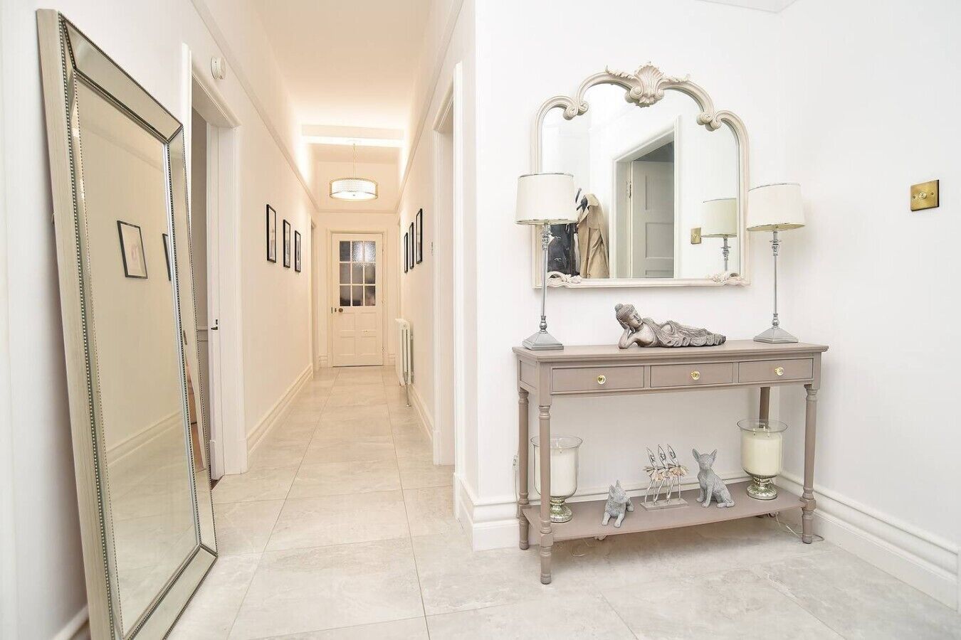 A hallway with a vanity table, a mirror, and a door.