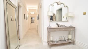 A hallway with a vanity table, a mirror, and a door.