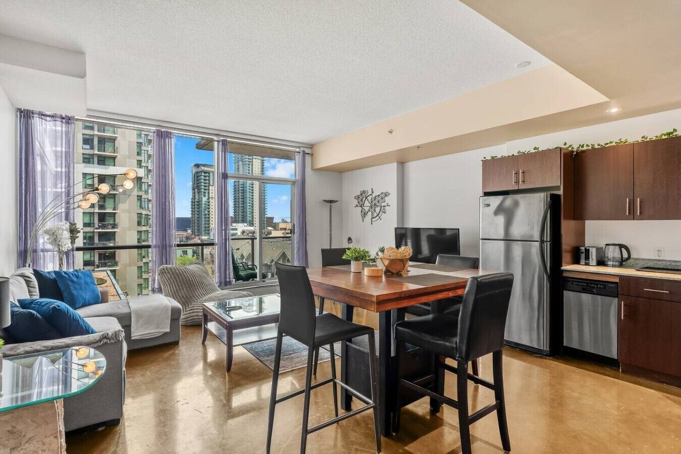 Un appartement moderne comprenant un coin repas, une cuisine et une grande fenêtre donnant sur la ville.