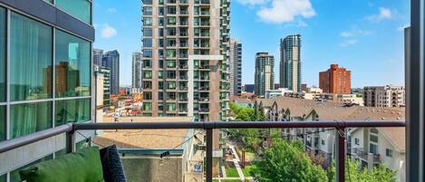 A balcony with a view of high-rise buildings and a landscaped area.