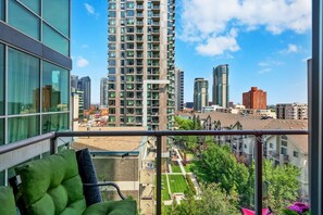 A balcony with a view of high-rise buildings and a landscaped area. - 2 Bed 2 Bath | Mins to Stampede | AC (Calgary)
