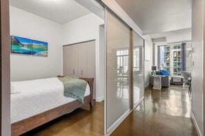 A bedroom with a bed, a wardrobe, a sliding door leading to a balcony, and a painting on the wall. - 2 Bed 2 Bath | Mins to Stampede | AC (Calgary)