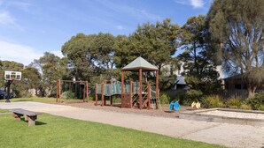 Ein Spielplatz mit Schaukeln, Klettergerüst und einem Basketballkorb.