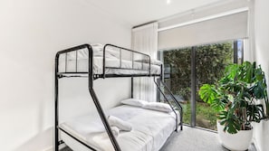Ein Schlafzimmer mit Etagenbetten, einem großen Fenster und einem Blumentopf.
