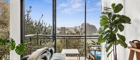 A balcony with a view of a cityscape, a wooden deck, and a bed with a view.