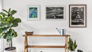 A room with a wooden table, a potted plant, and three framed artworks on the wall. - Coastal Resort Style Living Golf Tennis Pool & Beach (Torquay)