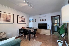 A modern living room with a dining area, a flat-screen TV, and a potted plant. - Cozy Historical Andalusian 3BR House Peachy Stays (Mijas)