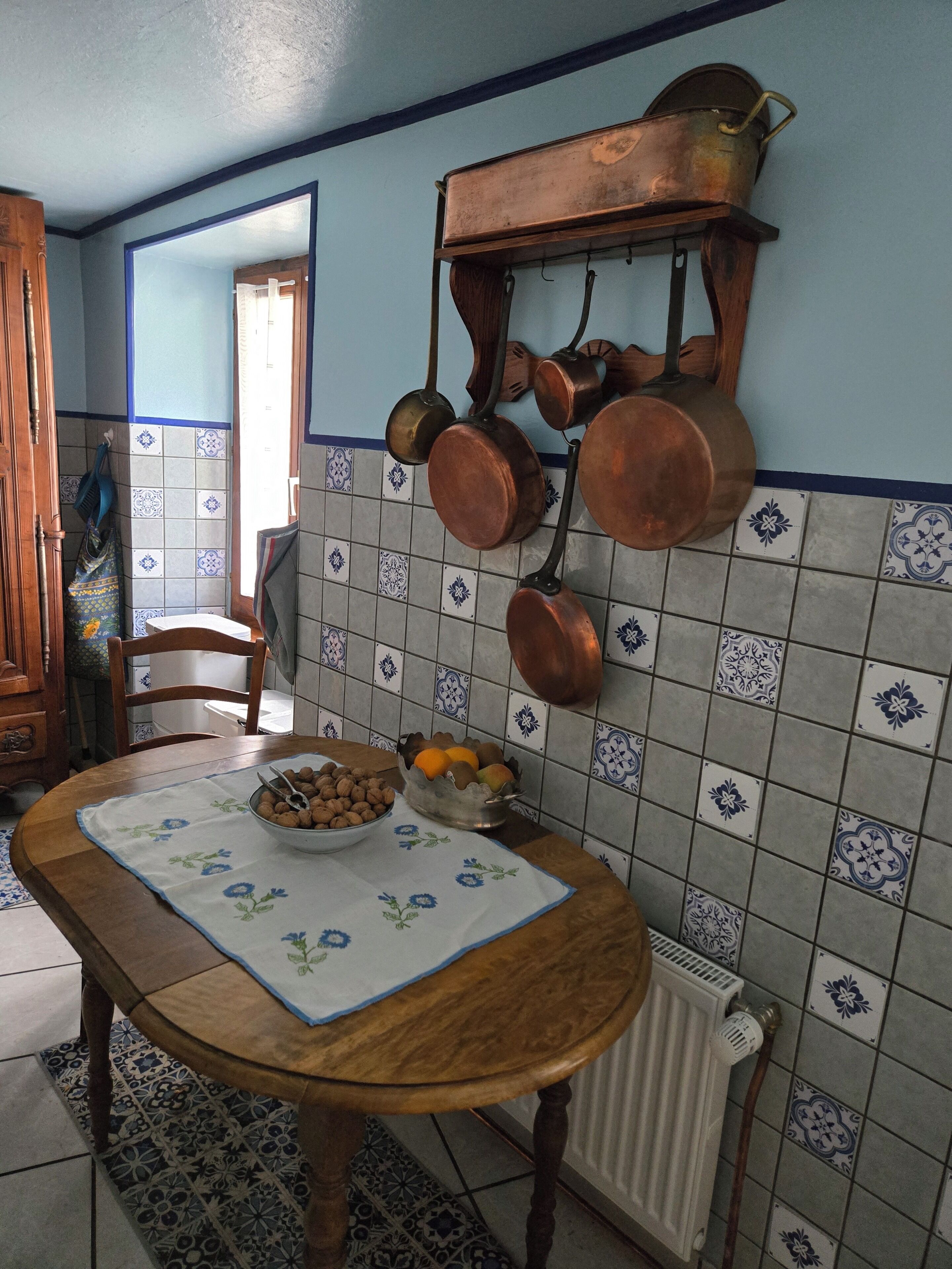Una cocina con una mesa de madera, un cuenco de nueces y un frutero.