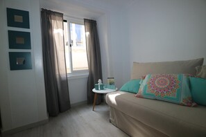 A room with a bed, a window with curtains, a small table with a book, and wall-mounted light switches. - Central Apartment "Casa Dos Lagares" (Lisbon)