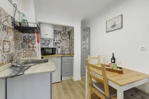 A compact kitchen with a sink, microwave, and a small dining area with a wooden table and chairs. - Central Apartment "Casa Dos Lagares" (Lisbon)