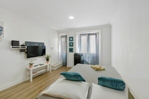 Un dormitorio moderno con cama, televisor, escritorio y ventana.