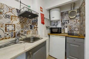 A compact kitchen with a sink, a microwave, and a dish rack. - Central Apartment "Casa Dos Lagares" (Lisbon)