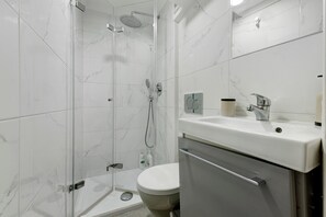 Un baño moderno con ducha, inodoro y lavamanos.
