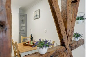 A dining table with a bottle of wine, glasses, and a box of tea. There are chairs around the table and a potted plant on the side. - Central Apartment "Casa Dos Lagares" (Lisbon)