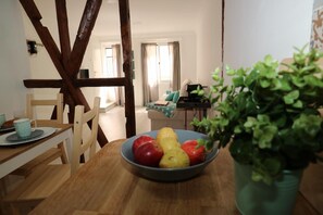 A dining area with a wooden table, chairs, a bowl of fruit, and a potted plant. - Central Apartment "Casa Dos Lagares" (Lisbon)