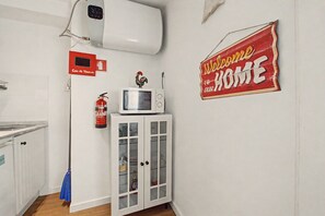 A kitchen with a microwave, a fire extinguisher, and a cabinet with glass doors. - Casa Beco Do Castelo (Lisbon)