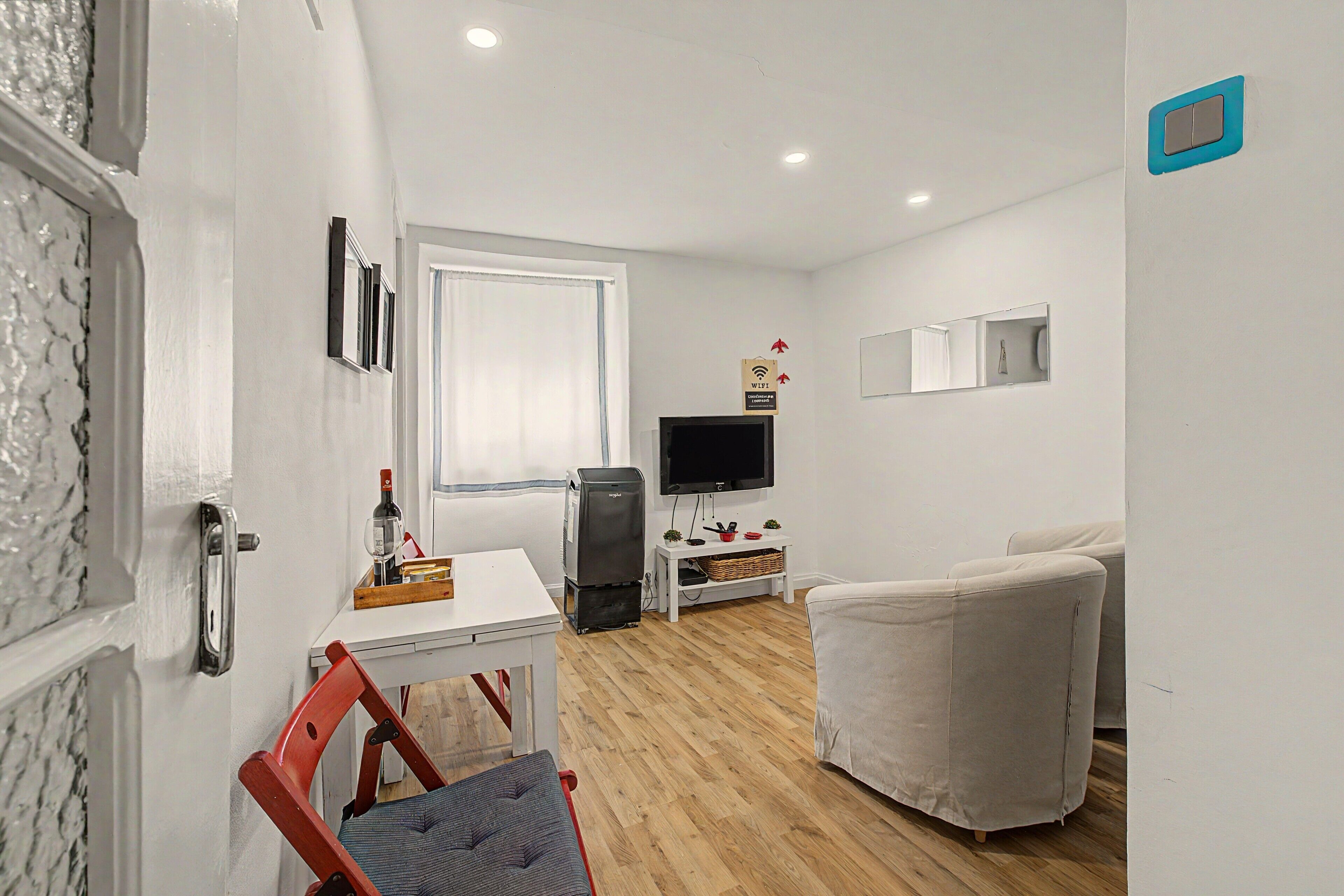 Un salon moderne avec un canapé blanc, une table à manger et un téléviseur.
