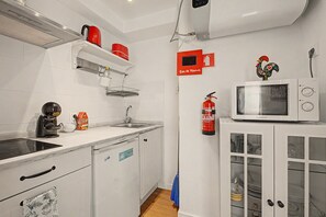 A kitchen with white cabinets, a microwave, a kettle, and a fire extinguisher. - Casa Beco Do Castelo (Lisbon)