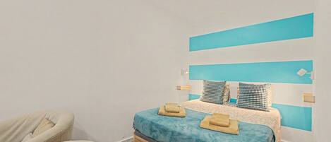 Een slaapkamer met een bed, een stoel en een blauwe accentmuur.